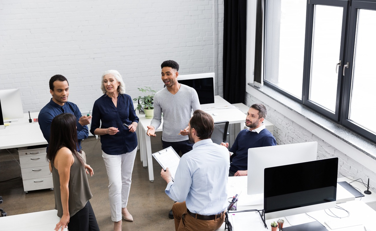 Team of developers collaborating in a modern office, with a mentor guiding junior developers on a coding project.